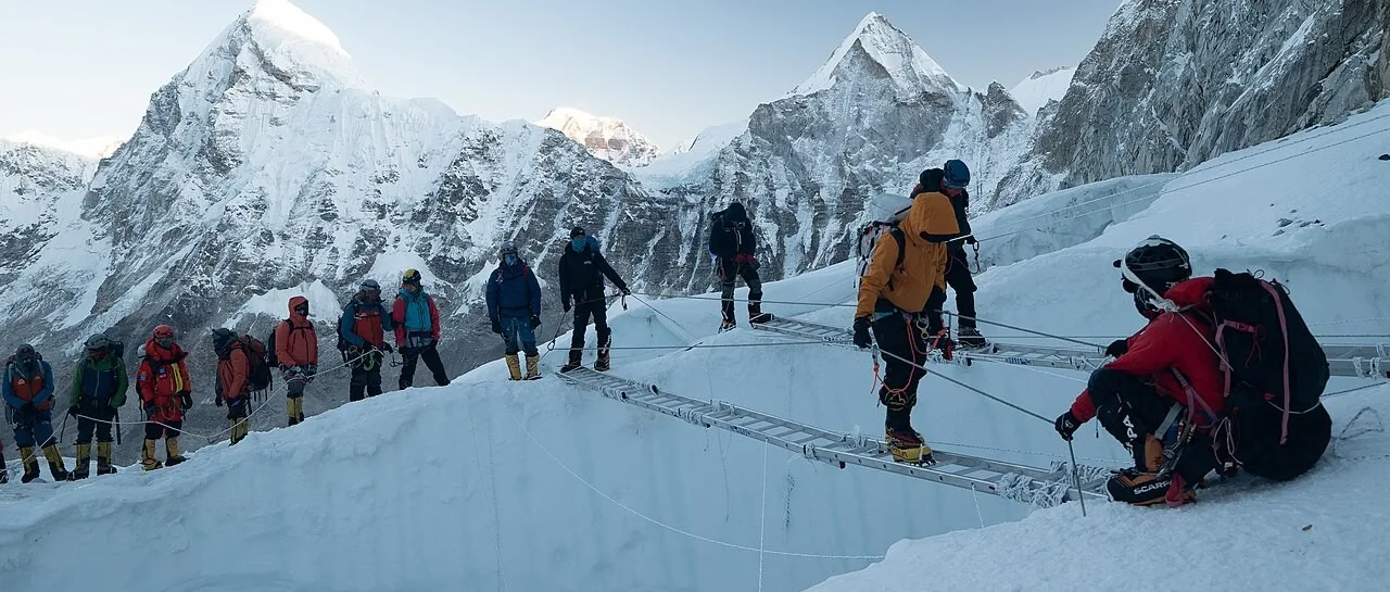 Climbers crossing ladders over crevasses in the Khumbu Icefall on Mount Everest
